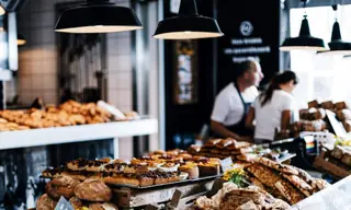 Comptoir de boulangerie garni de pains et de viennoiseries, l'équipe en service