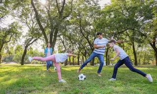 Enfants et adultes jouant au football dans un parc